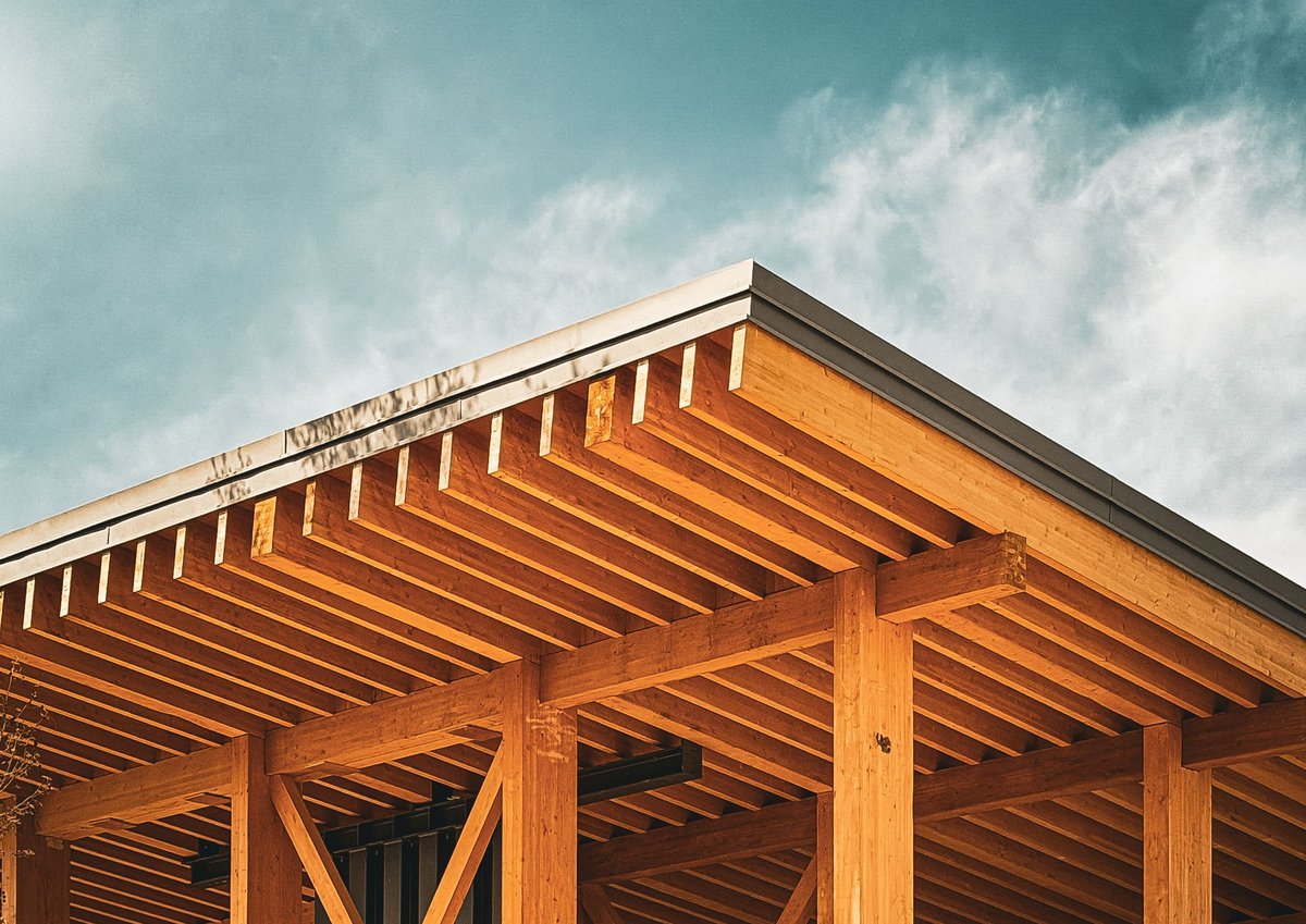 A wood-framed building's roofline under construction against a blue sky